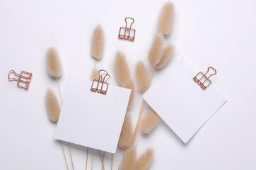 Memo white square sheets of paper with binder clips with lagurus flowers on white background