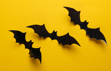 Halloween decoration concept. Black paper bats flying on yellow background. Top view