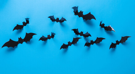 Fototapeta premium Halloween decoration concept. Black paper bats flying on blue background. Top view