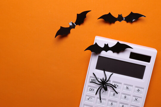 White calculator with halloween decor on orange background