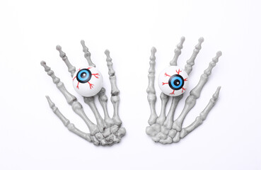Fototapeta premium Halloween decoration concept. Plastic skeleton hands holding eyeballs on white background