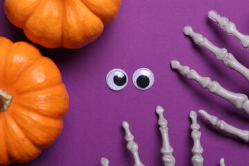 Staring scared eyes and halloween decor on purple background. Flat lay