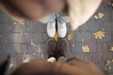 Top view of feet in shoes of a couple in love among autumn fallen leaves