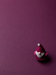 Small red Santa hat placed on a white plate against a plain white background, minimal festive decor.