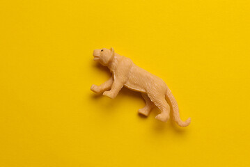 Plastic toy tiger figurine on yellow background