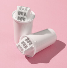 Cartridge filters for water filtration on pink background.