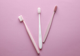 Plastic and eco bamboo toothbrushes on pink background. Top view