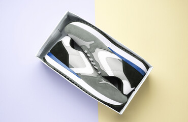 New Gray running shoes on with box on pastel background. Casual sneakers.