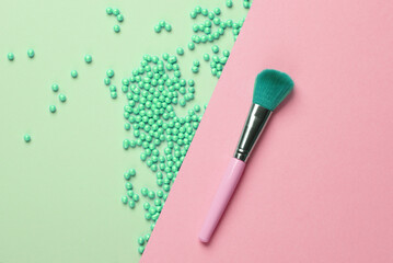 Makeup golden powder balls and brush on pink blue background. Beauty concept. Top view