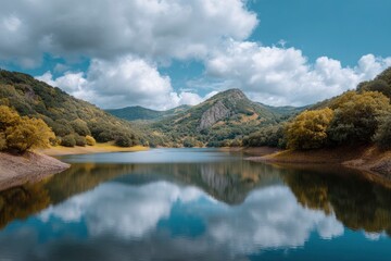 Fototapeta premium Still Lake Reflecting Mountains and Cloudy Sky in Serene Landscape