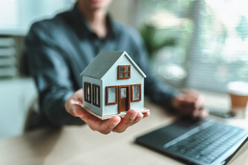 Home salesman, insurance salesman Holding a house in hand. Assets, real estate, loans and property concept.