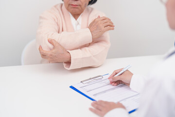 Elderly Woman having elbow ache and consulting doctor in hospital. muscle pain due to lateral epicondylitis or tennis elbow. injury, Health and medical consultation concept