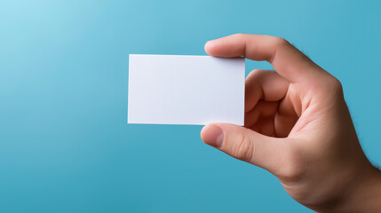 Hand holding a blank white business card against a blue background.
