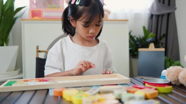 Asian girl playing with colorful puzzle blocks at home, promoting early childhood education, brain development, and cognitive skills through creative and tactile learning activities.
