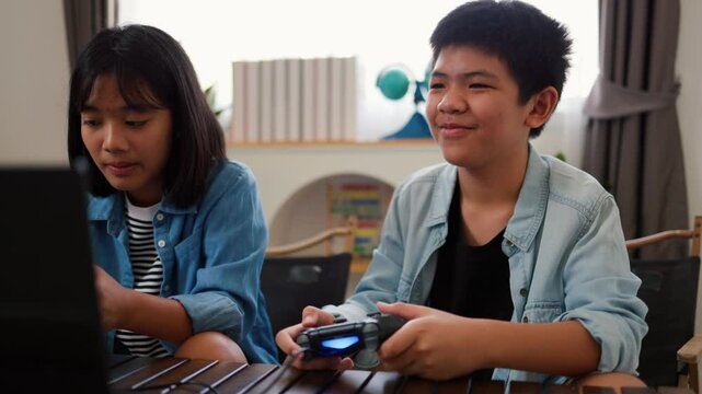 Asian teenage boy and girl playing video games at home together. Concept of digital lifestyle, esports, fun learning, teamwork, and modern entertainment for kids and teens indoors.