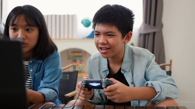 Asian teenage boy and girl playing video games at home together. Concept of digital lifestyle, esports, fun learning, teamwork, and modern entertainment for kids and teens indoors.