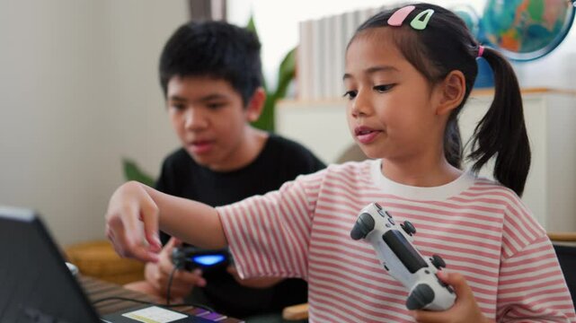 Asian teenage boy and girl playing video games at home together. Concept of digital lifestyle, esports, fun learning, teamwork, and modern entertainment for kids and teens indoors.