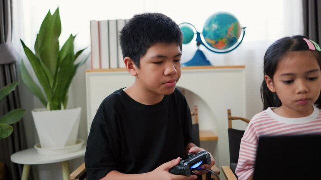 Asian teenage boy and girl playing video games at home together. Concept of digital lifestyle, esports, fun learning, teamwork, and modern entertainment for kids and teens indoors.