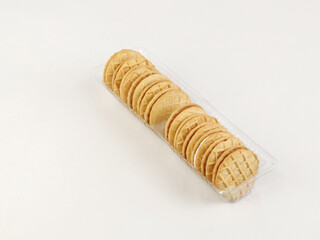 A row of round butter cookies neatly arranged in a transparent plastic tray on a clean white background.