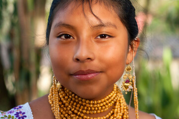 Indigenous girl wearing traditional clothing and jewelry posing outdoors