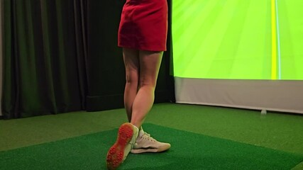 Woman practicing putting skills indoors using golf simulator technology during evening session