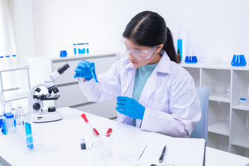 Female teen scientist holding test tubes and analyzing substance in clinical lab. Science,...