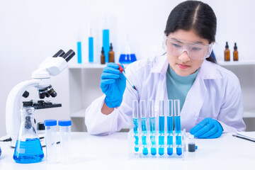 Scientist girl uses dropper to carefully handle blue chemical samples in a lab. Science,...