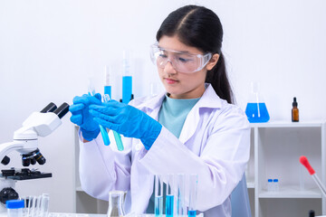 Fototapeta premium A teenage girl scientist in a laboratory carefully inspects liquid sample in pipette while wearing gloves and lab coat, involved in science, laboratory, scientist, experiment, and research, health.