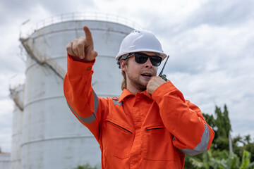 Man professional engineer technician in orange jumpsuit and white hard hat through Walkie Talkie...