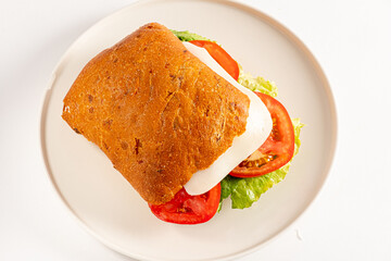 A tasty sandwich features fresh tomatoes, crisp lettuce, and soft cheese in artisan bread