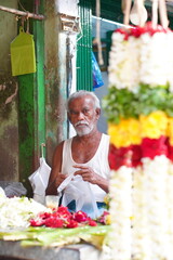 a potrait of garland maker in indian streets
