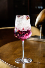 A charming cocktail on a polished table, glistening with ice and rose petals, perfect for relaxing