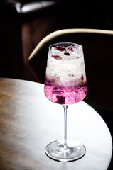 A refreshing cocktail adorned with petals rests on a wooden table, perfect for a chill evening