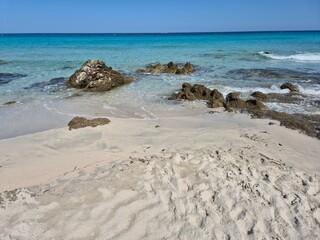 white sand, a few rocks and crystal clear water at the beach of plage de saleccia in corsica