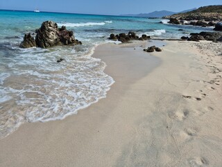 white sand, a few rocks and crystal clear water at the beach of plage de saleccia in corsica