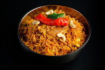 A beautifully arranged bowl of fragrant biryani features spices, nuts, and a vibrant red chili