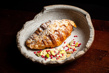A beautifully crafted pastry is artfully arranged with nuts and vibrant dried fruits