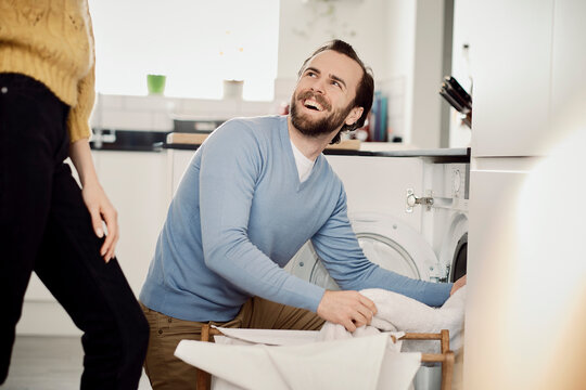 Couple happily doing laundry together in a kitchen