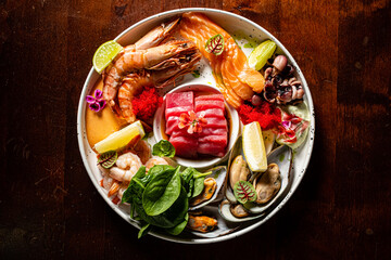 A vibrant seafood platter features fresh shrimp, oysters, and tuna garnished with lime