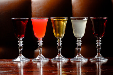 Five exquisite glasses filled with vibrant drinks stand proudly on a wooden table, inviting taste