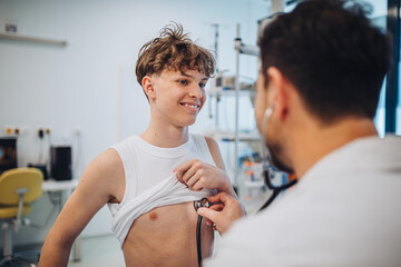 Teen boy undergoing medical checkup with doctor in hospital room.