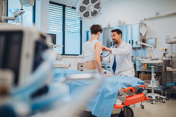 Teen boy undergoing medical checkup with doctor in hospital room.