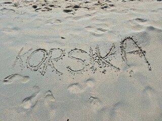 handwritten word "KORSIKA" in white sand