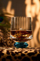 Leopard print tablecloth with glass whiskey glass and sunlight in the background