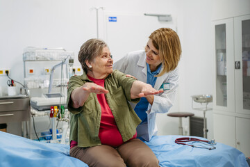 Geriatrician examining senior woman's mobility during routine check-up,