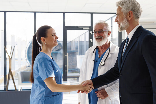 Medical sales representative presenting new medication to doctors, standing hospital hallway.