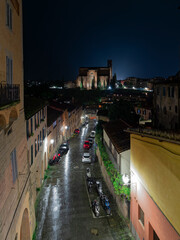 Basilica Cateriniana San Domenico church and the urban environment illuminated night view under a light rain. A romantic travel to Siena, Tuscany, Italy.