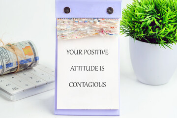 Positive Attitude Reminder Posted on a Desk Next to a Plant and Calculator Showcasing an Inspiring...