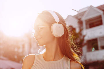 Young caucasian female enjoying music with headphones in sunlit urban setting