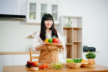Asian woman preparing healthy food with smartphone in home kitchen. Great for wellness, clean eating, cooking content